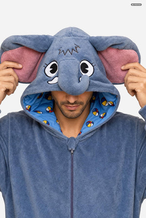 A man wearing a blue elephant-themed zip-up hooded onesie, holding the hood up to show the large floppy elephant ears with pink inner lining and a blue patterned interior.