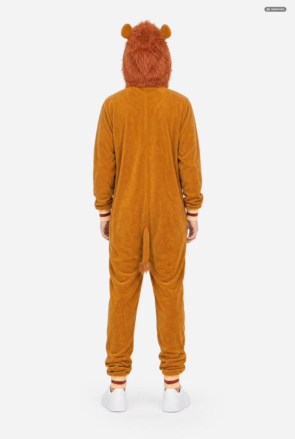 A person viewed from the back wearing a plush animal lion onesie in a warm camel-brown color, with small ears on the hood and white sneakers against a plain light gray studio background.