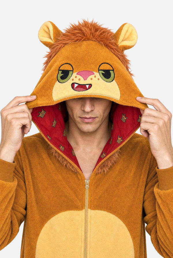 A man wearing a plush lion onesie pajama with a hood featuring a lion face and ears, a tan belly patch, and a red patterned hood lining, against a white background. Close up of the hood