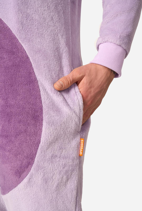 Close-up of a person wearing a fuzzy lavender one-piece garment with a large darker purple panel and a small orange tag reading 'Opposuits'.