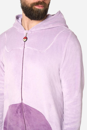 A close-up of a man wearing a light purple plush hooded one-piece jumpsuit with a darker purple panel at the bottom and a small red, white, and black circular detail near the zipper.