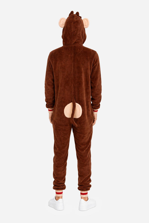 A man wearing a brown plush animal onesie with a hood shaped like a monkey face, featuring pink ears, a yellow inner hood lining, and a large tan belly patch on the front, photographed against a white studio background. View from the back.