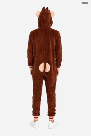 A person shown from the back wearing a brown plush animal onesie with a hood, pink ear details, and a pink tail patch on the back, photographed against a light gray studio background.