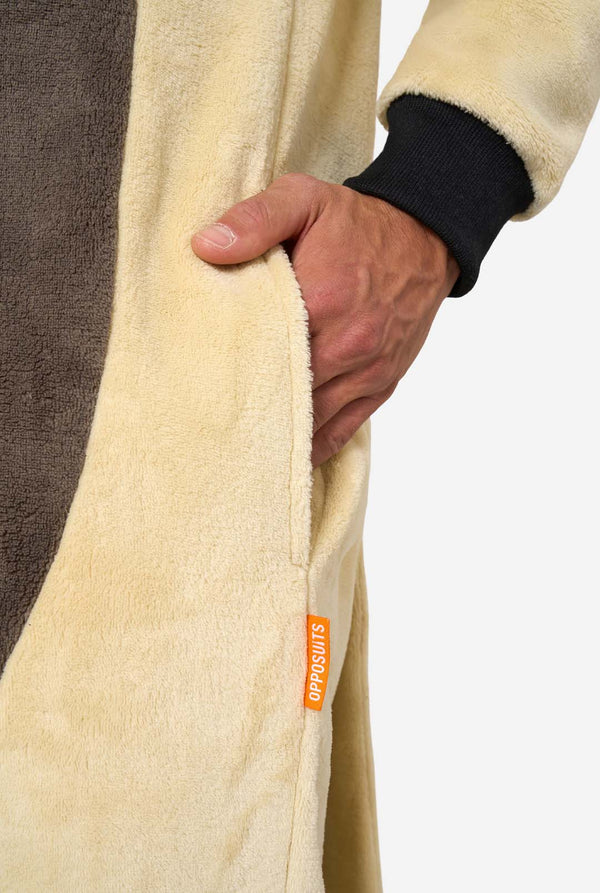 Close-up of man’s hand in the pocket of a beige Appa onesie with black cuff and orange “Opposuits” label.