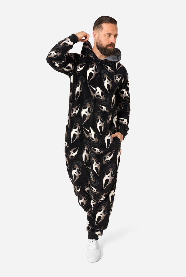 A man modeling a black one-piece hooded jumpsuit covered in a white shark print, standing against a light gray studio background.