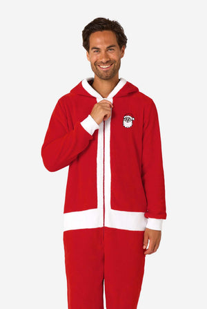 A smiling man models a cozy, red and white, hooded christmas onesie that resembles a Santa onesie.