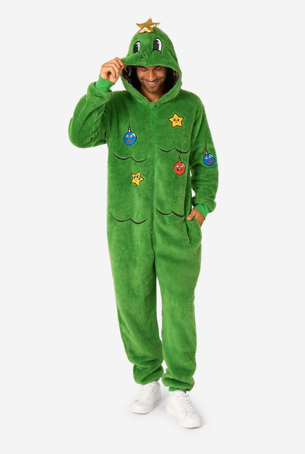 A smiling man wearing a green Christmas onesie designed to look like a Christmas tree, decorated with cartoon ornaments and stars. Hood on it's head, full body image