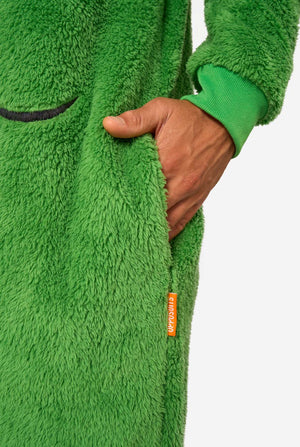 A smiling man wearing a green Christmas onesie designed to look like a Christmas tree, decorated with cartoon ornaments and stars. Close up of the pockets