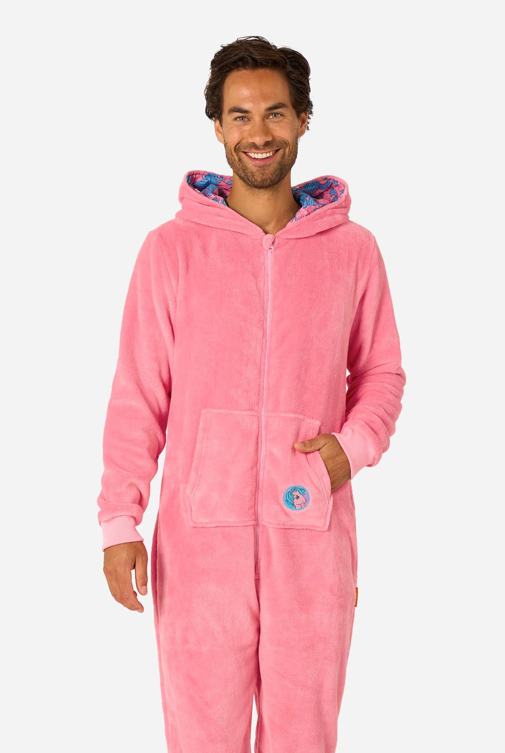 Man wearing a pink onesie with a My Little Pony design on a light background. Hood up