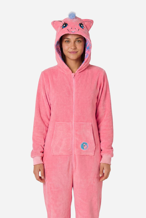 Woman wearing a pink onesie with a My Little Pony design on a light background. Hood up.