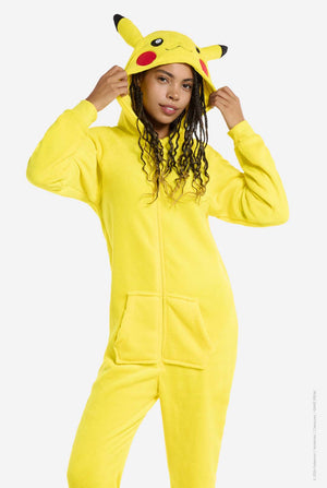 A woman is wearing a vibrant Pikachu onesie, designed to resemble the iconic Pokémon character. This unisex adult onesie is bright yellow with Pikachu’s recognizable face on the hood, featuring large black-tipped ears, black eyes, red cheeks, and a cute smile. The onesie has a convenient front zipper closure and two front pockets for functionality and comfort. Holding the hood with two hands. The soft, cozy material makes it perfect for lounging, cosplay events, or Pokémon-themed gatherings. 