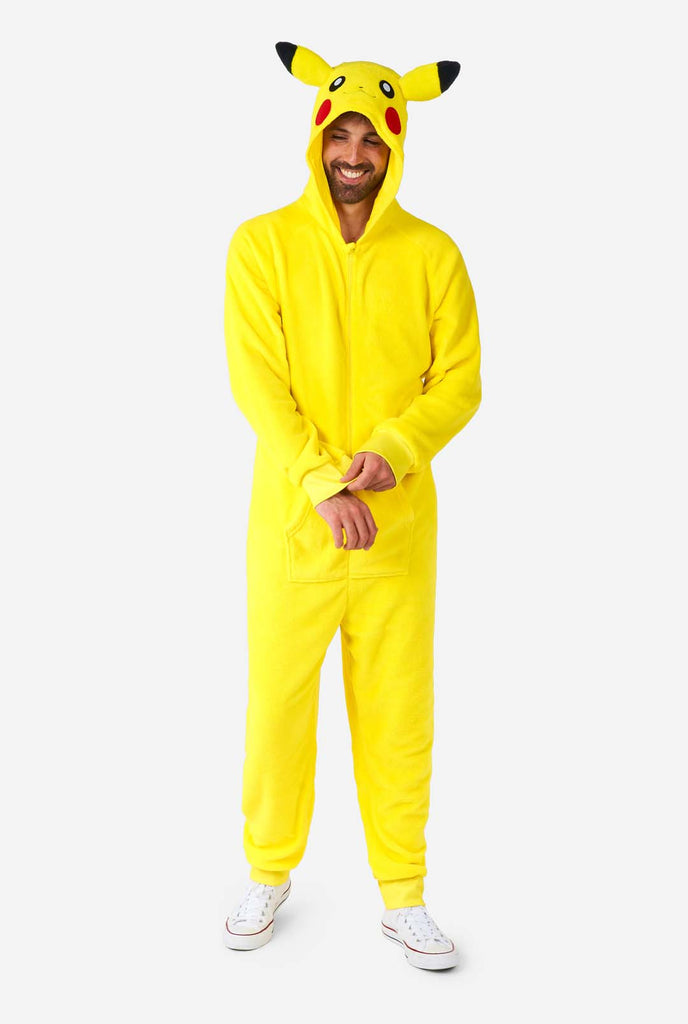 A man is wearing a vibrant Pikachu onesie, designed to resemble the iconic Pokémon character. This unisex adult onesie is bright yellow with Pikachu’s recognizable face on the hood, featuring large black-tipped ears, black eyes, red cheeks, and a cute smile. The onesie has a convenient front zipper closure and two front pockets for functionality and comfort. The soft, cozy material makes it perfect for lounging, cosplay events, or Pokémon-themed gatherings. Ideal for Pokémon fans. Full body image. 