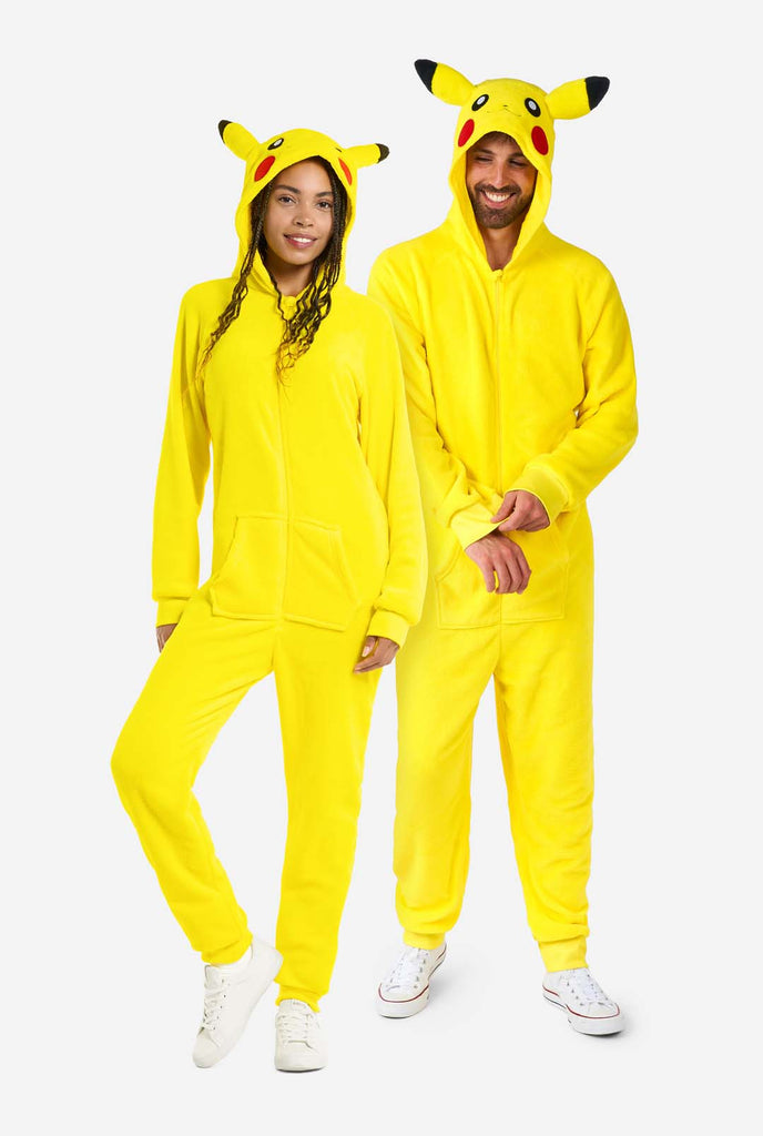 A man and woman are wearing a vibrant Pikachu onesie, designed to resemble the iconic Pokémon character. This unisex adult onesie is bright yellow with Pikachu’s recognizable face on the hood, featuring large black-tipped ears, black eyes, red cheeks, and a cute smile. The onesie has a convenient front zipper closure and two front pockets for functionality and comfort. The soft, cozy material makes it perfect for lounging, cosplay events, or Pokémon-themed gatherings. Ideal for Pokémon fans. Full boy image.