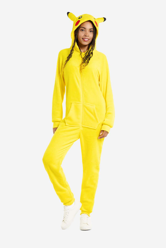 A woman is wearing a vibrant Pikachu onesie, designed to resemble the iconic Pokémon character. This unisex adult onesie is bright yellow with Pikachu’s recognizable face on the hood, featuring large black-tipped ears, black eyes, red cheeks, and a cute smile. The onesie has a convenient front zipper closure and two front pockets for functionality and comfort. The soft, cozy material makes it perfect for lounging, cosplay events, or Pokémon-themed gatherings. Ideal for Pokémon fans. Full body image.