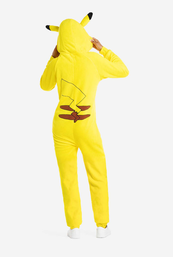 A woman is wearing a vibrant Pikachu onesie, designed to resemble the iconic Pokémon character. This unisex adult onesie is bright yellow with Pikachu’s recognizable face on the hood, featuring large black-tipped ears, black eyes, red cheeks, and a cute smile. The onesie has a convenient front zipper closure and two front pockets for functionality and comfort. The soft, cozy material makes it perfect for lounging, cosplay events, or Pokémon-themed gatherings. Ideal for Pokémon fans., view from the back.