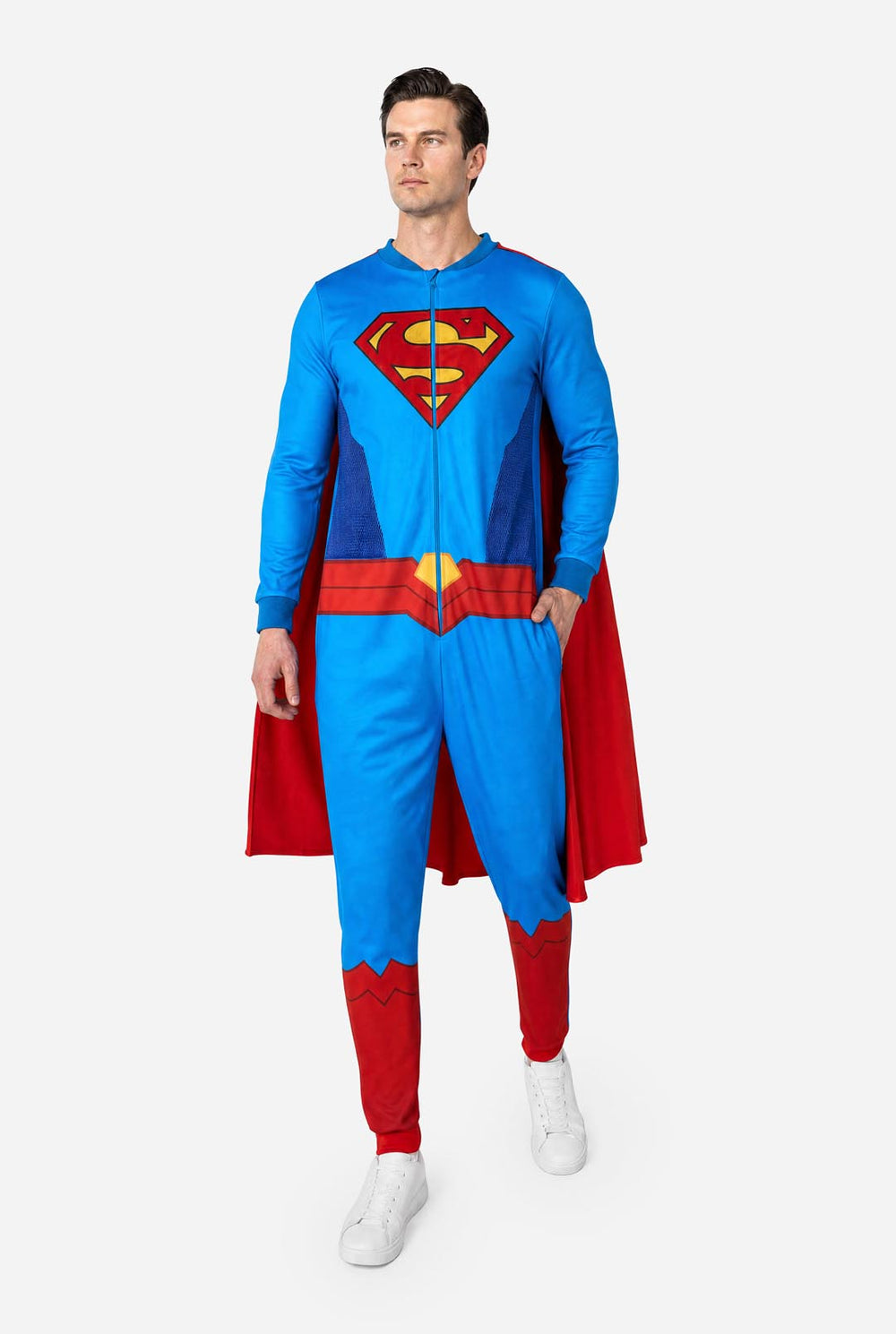 Image of a man wearing a blue and red Superman onesie with a red cape on a light background.