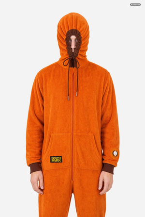 A smiling man wearing an orange South Park Kenny onesie with brown drawstrings and cuffs, standing against a light gray background. A small patch on the left leg reads 'South Park'. Hood closed.