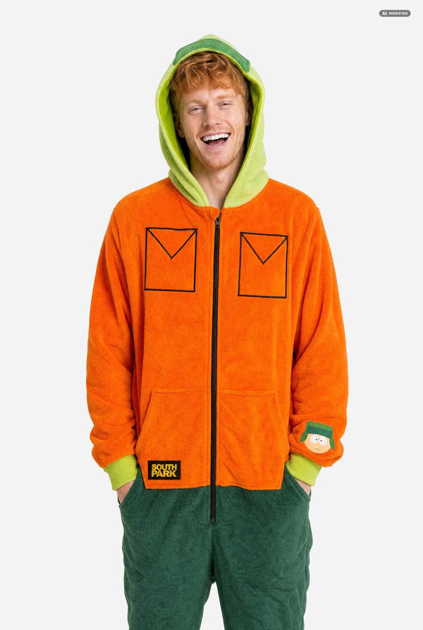 A man wearing a bright orange South Park Kyle onesie costume with lime green hood lining and cuffs, plus dark green pants, photographed against a light gray studio background.