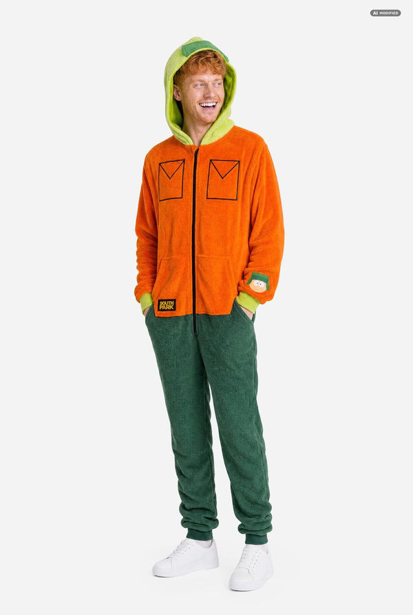 A man wearing a bright orange South Park Kyle onesie costume with lime green hood lining and cuffs, plus dark green pants, photographed against a light gray studio background. Full body image.