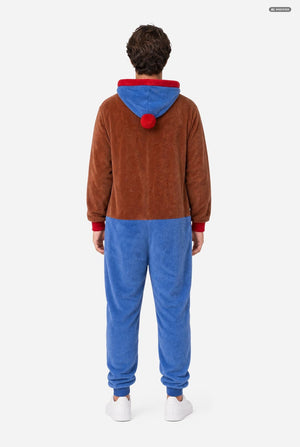A person shown from the back wearing a brown and blue hooded one-piece pajama or costume with red trim and a red pom-pom, photographed against a plain light gray studio background.