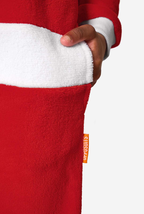 Close-up of a child’s hand in the pocket of a red Santa onesie, showing the white waistband trim and an orange OppoSuits label.