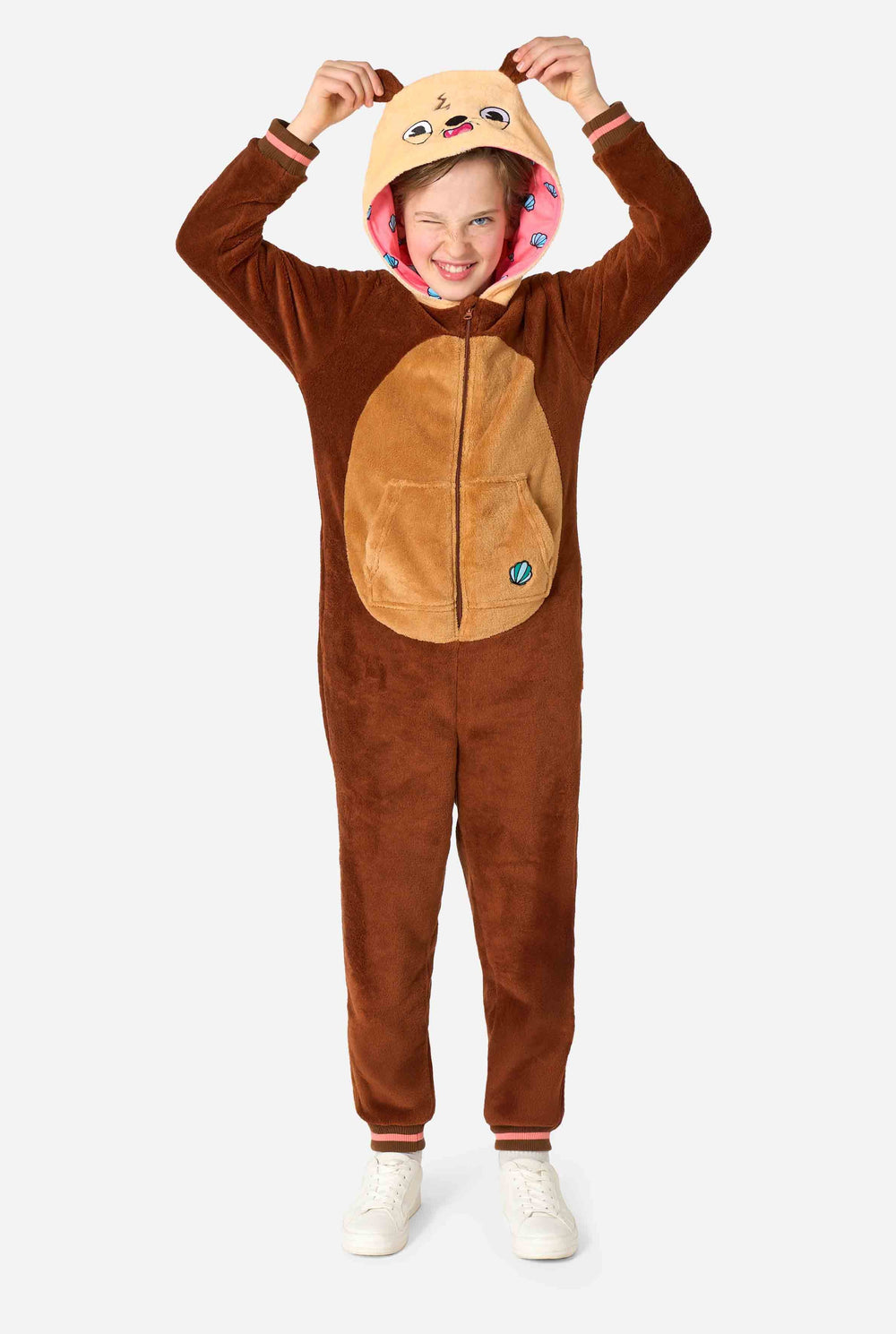 A smiling kid is wearing a brown kids onesie designed as an otter. The onesie features a hood with ears, a cute face, and playful otter details.