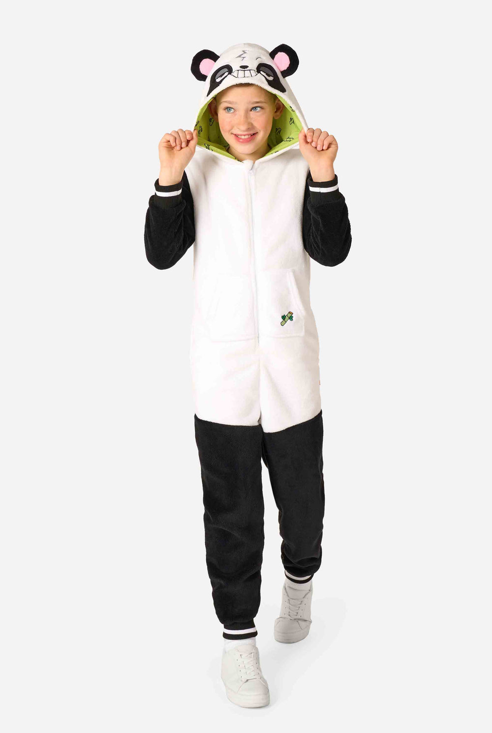 A smiling kid wearing a panda-themed kids onesie. This cozy onesie features black and white panda colors with a playful hood showcasing panda ears and a cute face. Perfect for lounging or fun costume occasions.