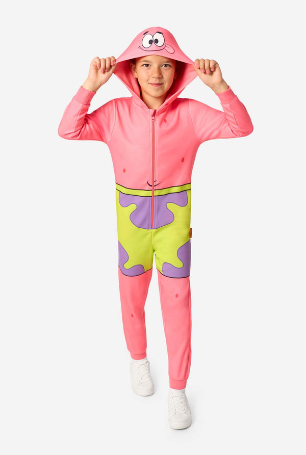 Full-body front view of a child in a pink Patrick Star onesie with a cartoon face on the hood and purple-and-green shorts print, holding the hood with both hands.
