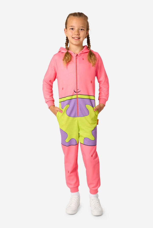 Child standing in a pink Patrick Star onesie with cartoon shorts design, hands in pockets and smiling forward.