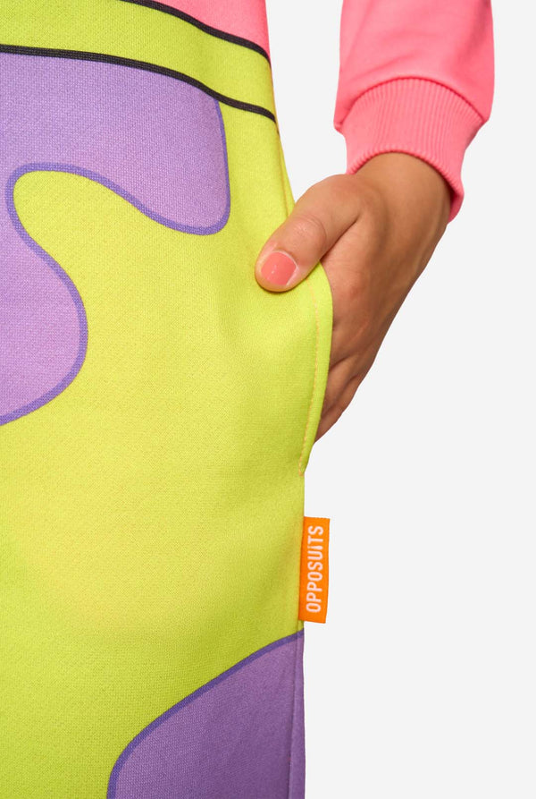Close-up of the neon green and purple shorts print on the Patrick Star onesie, showing the child’s hand in the pocket and the orange Opposuits label.