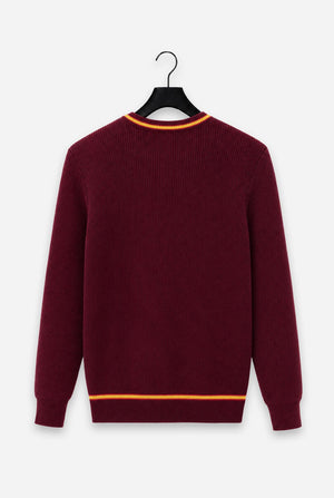 A maroon ribbed knit Harry Potter Gryffindor sweater with orange contrast trim at the crew neck and hem, hanging on a black hanger against a light gray background.