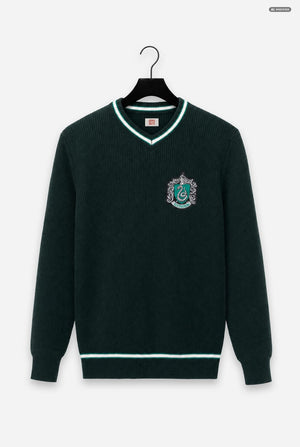 A dark forest green ribbed knit sweater with a V-neck, featuring light green and white trim and a Slytherin crest embroidered on the left chest, displayed on a black hanger against a light gray background.