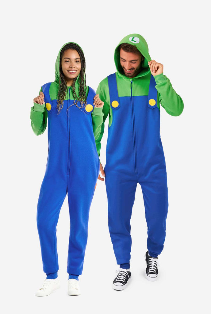 A man and a woman are dressed in a Luigi-themed onesie. The outfit looks as a bright green hoodie with an "L" symbol on the hood and blue overalls with large yellow buttons on the straps. The overall design mimics the look of the popular video game character Luigi, with contrasting green and blue colors. The background is plain, putting focus on the costume. Full body image.