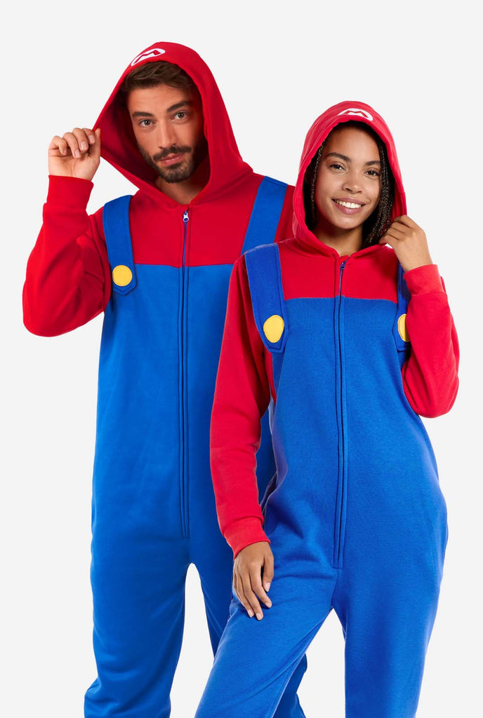 Man and Woman wearing red and blue, Unisex Adult Onesie with Super Mario theme. Onesie resembles the 
 Super mario outfit.