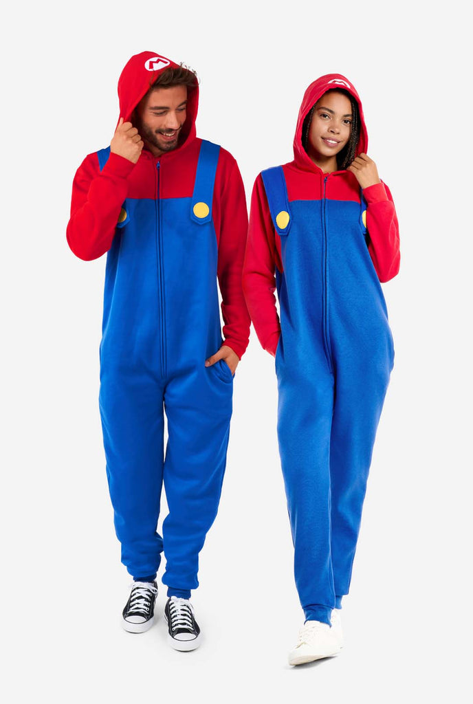 Man and Woman wearing red and blue, Unisex Adult Onesie with Super Mario theme. Onesie resembles the 
 Super mario outfit. Full body image.