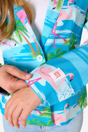 Image with a light background and a woman wearing a light blue blazer with tropical flamingo print and jeans. Sleeve close up.