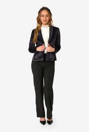 Woman wearing a black velvet blazer, black pants, and a white shirt on a white background