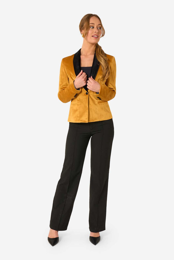Woman wearing a velvet golden blazer with black lapels on a white background, full body image. 