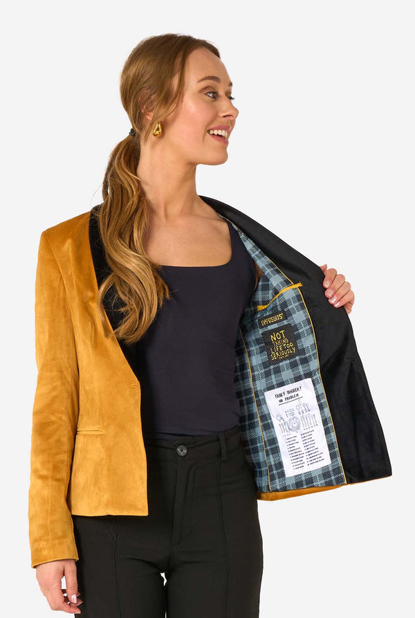 Woman wearing a velvet golden blazer with black lapels on a white background, opening one side of the jacket.