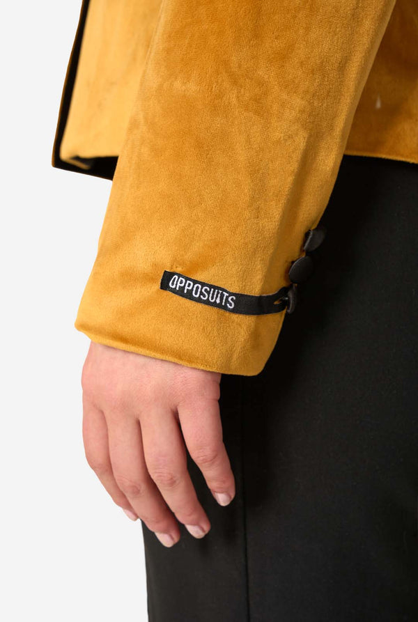 Woman wearing a velvet golden blazer with black lapels on a white background, sleeve close up.