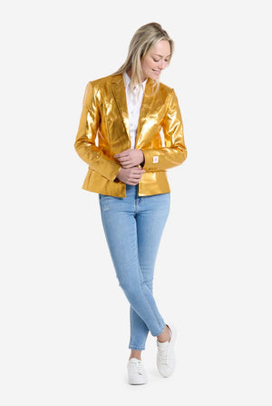 Woman wearing a shiny gold blazer, white shirt, blue jeans, and white sneakers on a white background