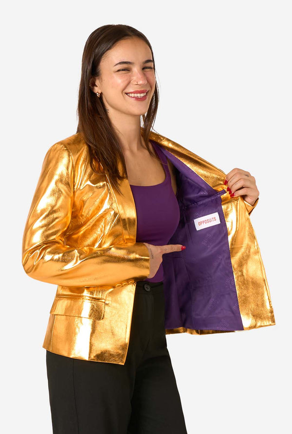 Woman wearing a gold blazer with a purple lining, holding a purple bag with a brand logo.