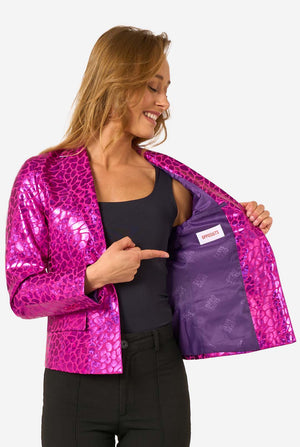Close-up of the woman pointing to the purple interior lining of the shiny hot-pink textured blazer, showing the Opposuits label.