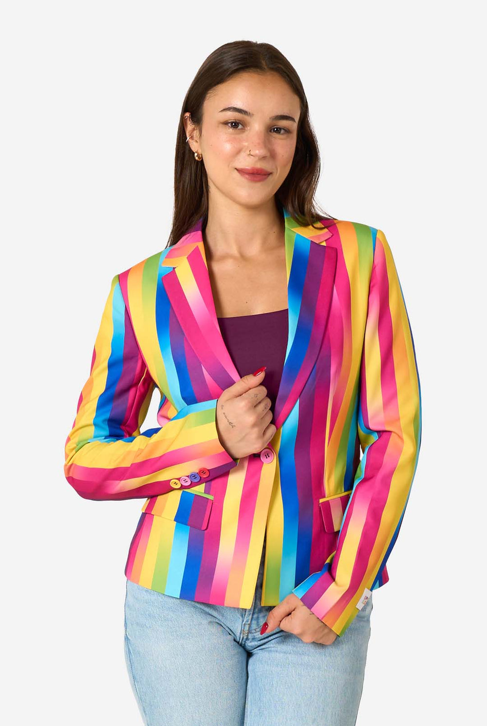 Woman wearing a colorful rainbow striped blazer and light blue jeans against a white background.