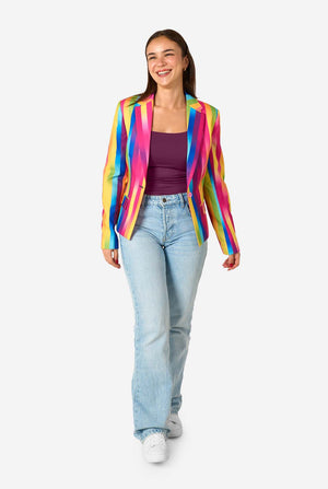 Woman wearing a colorful rainbow striped blazer and light blue jeans against a white background. Full body image.