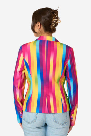 Woman wearing a colorful rainbow striped blazer and light blue jeans against a white background. View from the back.