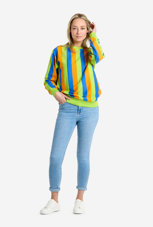 Woman wearing a colorful striped sweater and light blue jeans on a white background