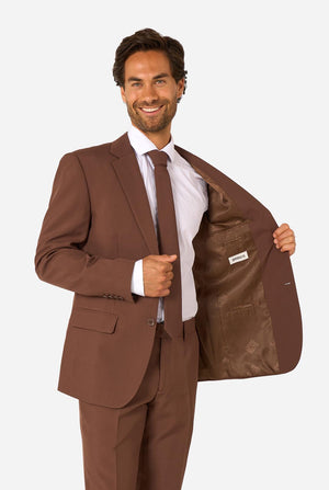 Man smiling while wearing a brown suit and white shirt, holding the jacket open to show the brown inner lining.