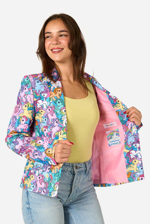 Woman wearing a colorful patterned My Little Pony blazer on a light background. Holding one side of the jacket open.