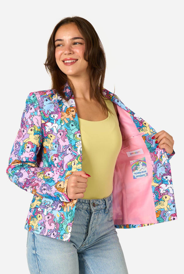 Woman wearing a colorful patterned My Little Pony blazer on a light background. Holding one side of the jacket open.